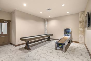 A game room with a shuffleboard table and a bench